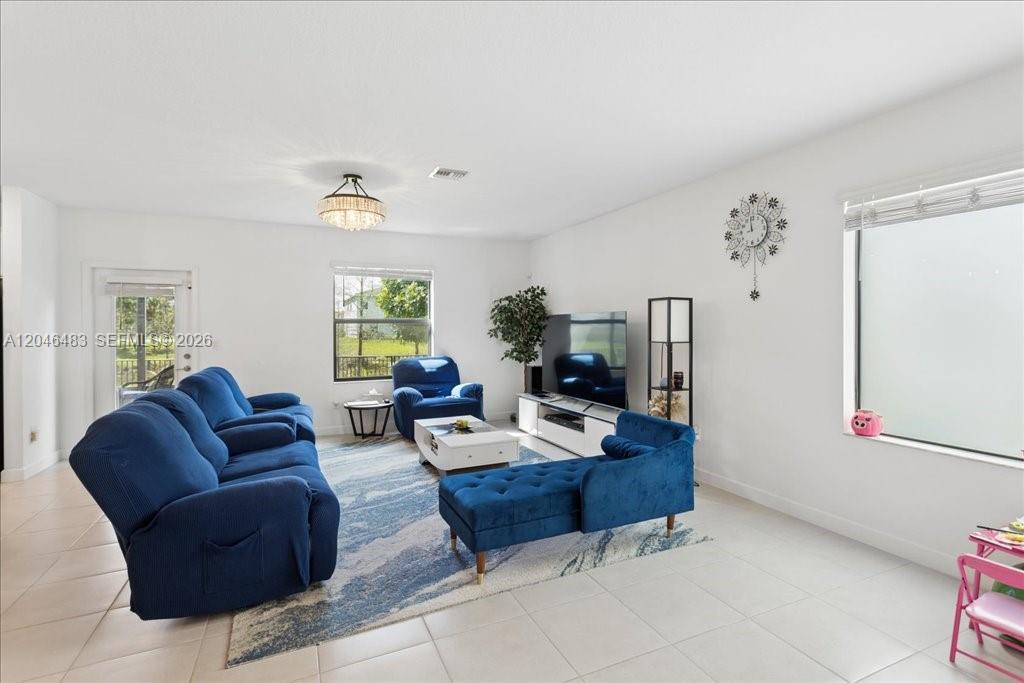A living room features blue furniture, a white coffee table, and a large television — 6018 Henderson Way, West Palm Beach FL 33415, WEST PALM BEACH, FL