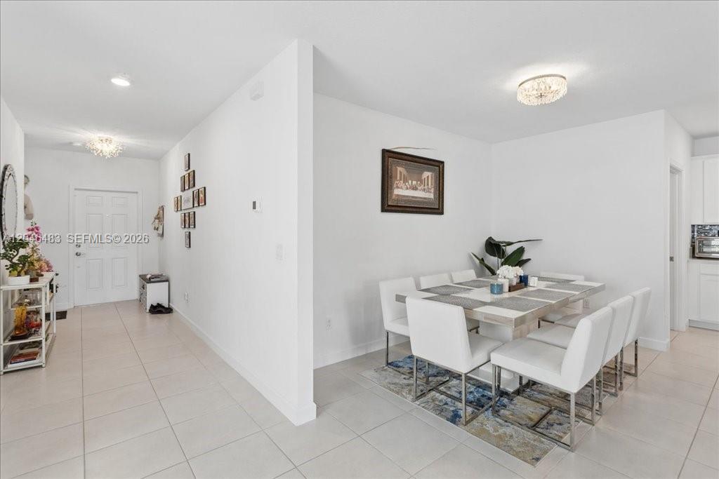 A dining area with a white table and chairs sits next to a tiled hallway — 6018 Henderson Way, West Palm Beach FL 33415, WEST PALM BEACH, FL