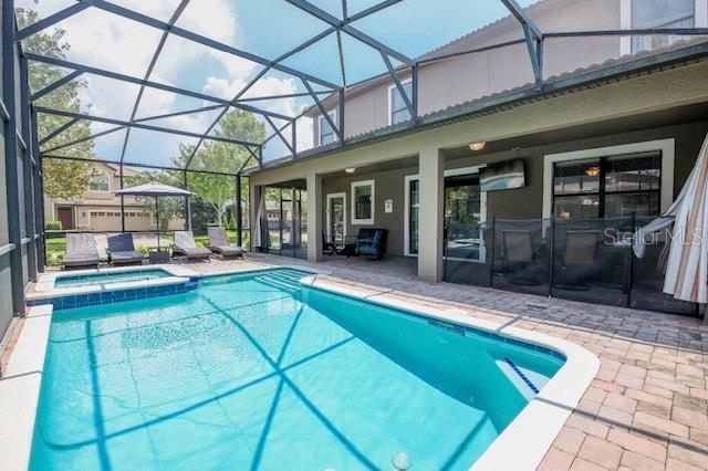 A backyard swimming pool with a spa is enclosed by a screened lanai and patio — 9101 EL CARO LANE, DAVENPORT, FL