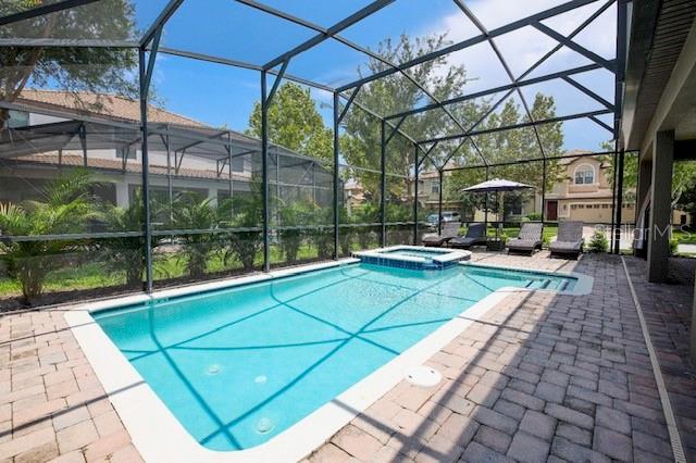 A screened-in swimming pool and spa with a brick paver deck in a backyard — 9101 EL CARO LANE, DAVENPORT, FL