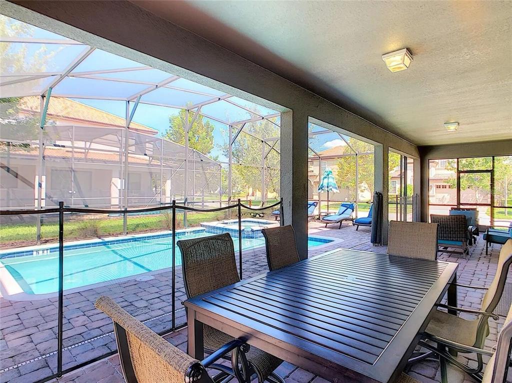 A covered patio features a dining set, a pool, and a spa inside a screened enclosure — 9101 EL CARO LANE, DAVENPORT, FL