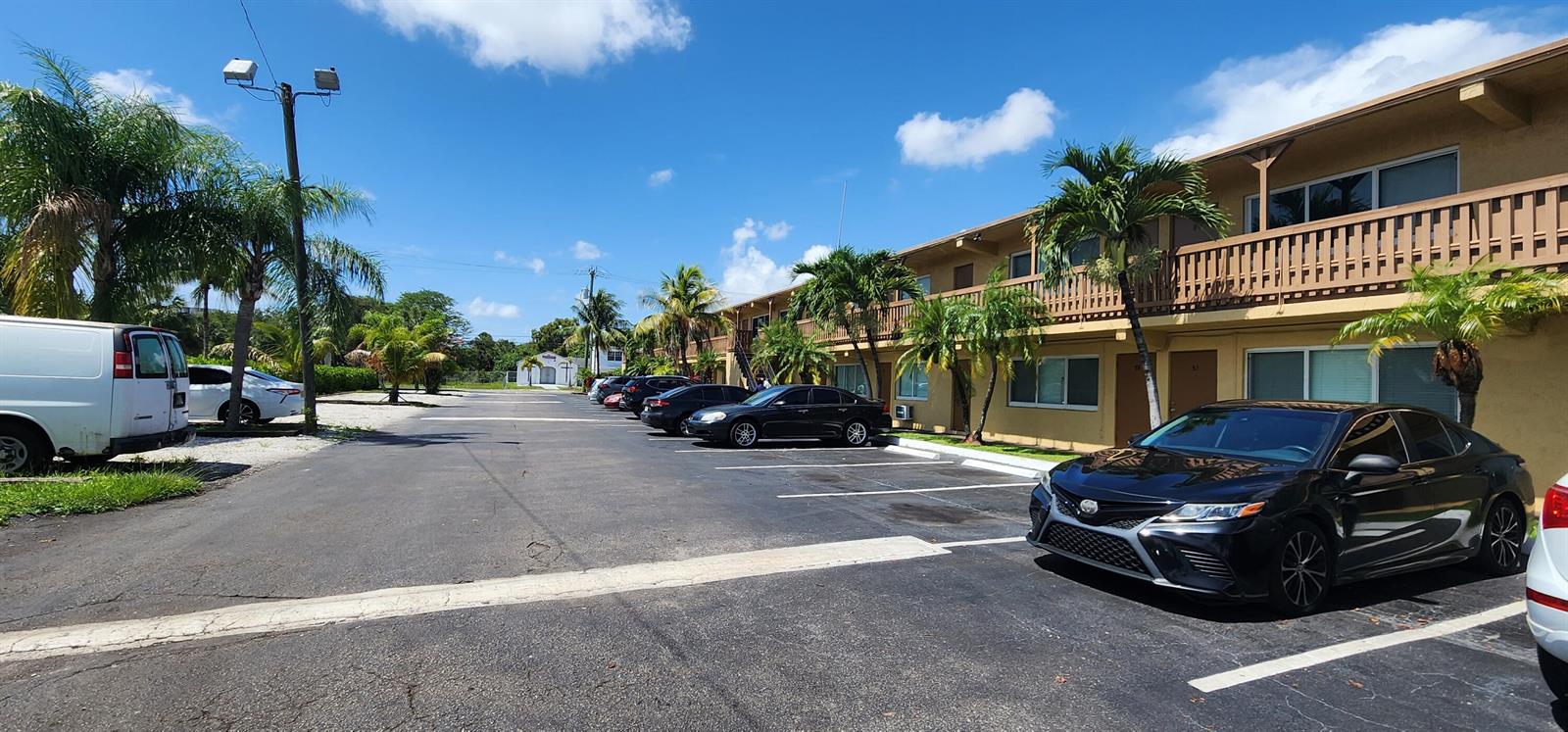 A parking lot sits in front of a two-story apartment building with palm trees — 620 NW 7th Avenue # 16, Pompano Beach FL 33060, POMPANO BEACH, FL