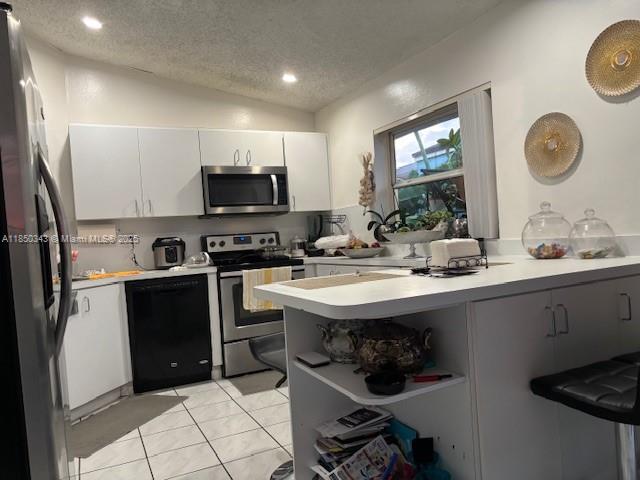 A kitchen features white cabinets, stainless steel appliances, a black dishwasher, and a breakfast bar — 21024 SW 118th Pl, Miami FL 33177, MIAMI, FL