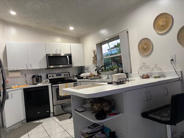 A kitchen features white cabinetry, stainless steel appliances, and a breakfast bar with stools — 21024 SW 118th Pl, Miami FL 33177, MIAMI, FL