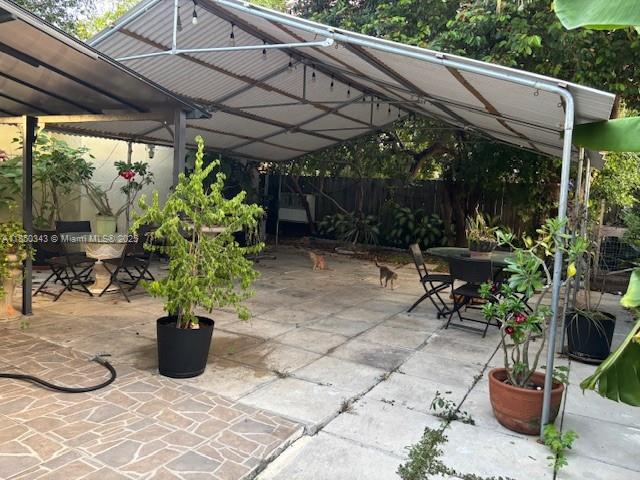 A covered outdoor patio features a metal roof, concrete pavers, and potted plants — 21024 SW 118th Pl, Miami FL 33177, MIAMI, FL