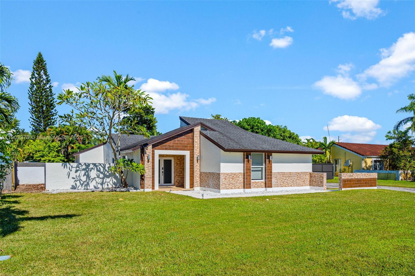 A single-story house with a stone-accented facade, a recessed entryway, and a large front lawn — 15281 SW 153rd St, Miami FL 33187, MIAMI, FL