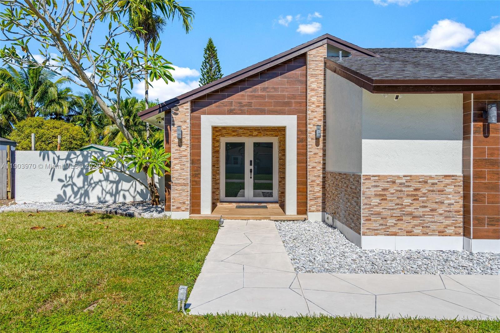 The exterior of a house features a stone-accented entryway with double glass doors — 15281 SW 153rd St, Miami FL 33187, MIAMI, FL
