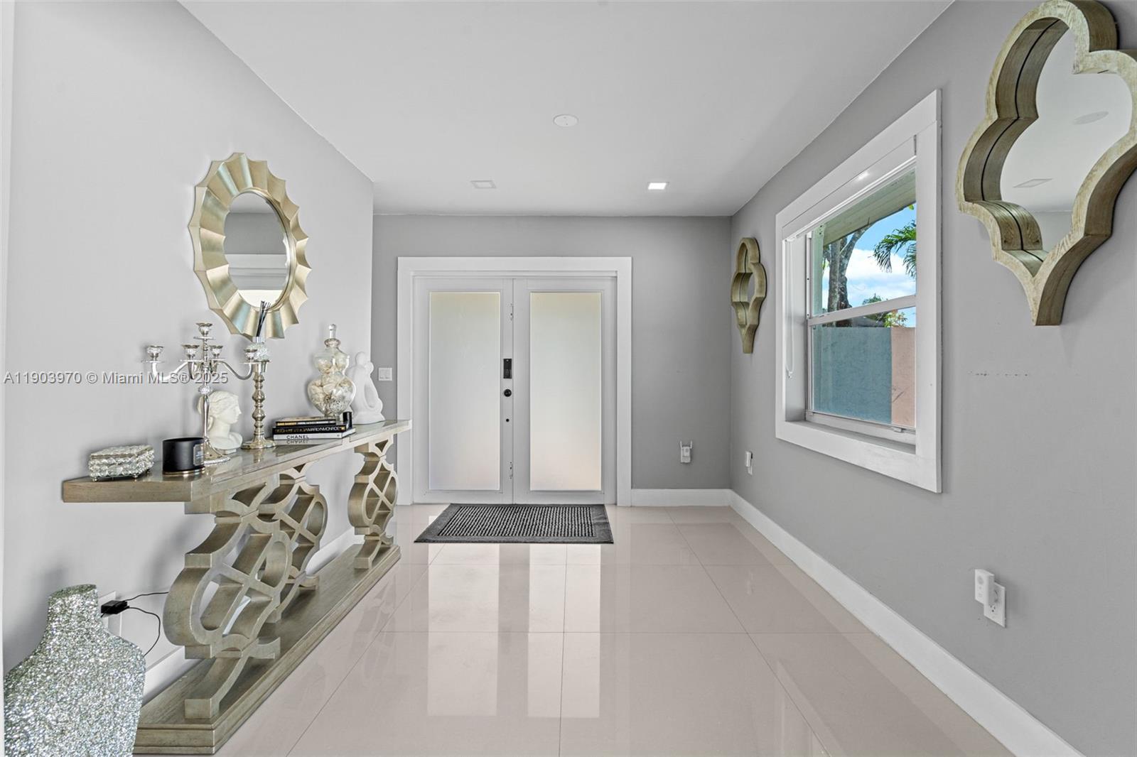 A bright entryway features light gray walls, white tile floors, and a decorative console table — 15281 SW 153rd St, Miami FL 33187, MIAMI, FL