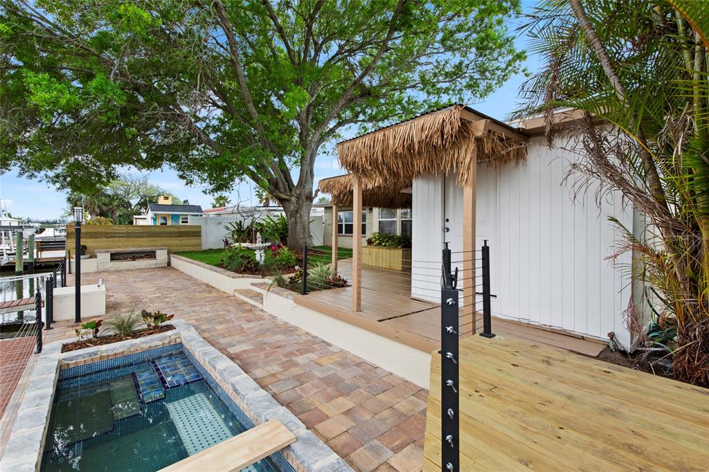 A backyard patio features a small tiled pool, a wooden deck, and a tiki-style roof — 13626 ALLYN DRIVE, HUDSON, FL