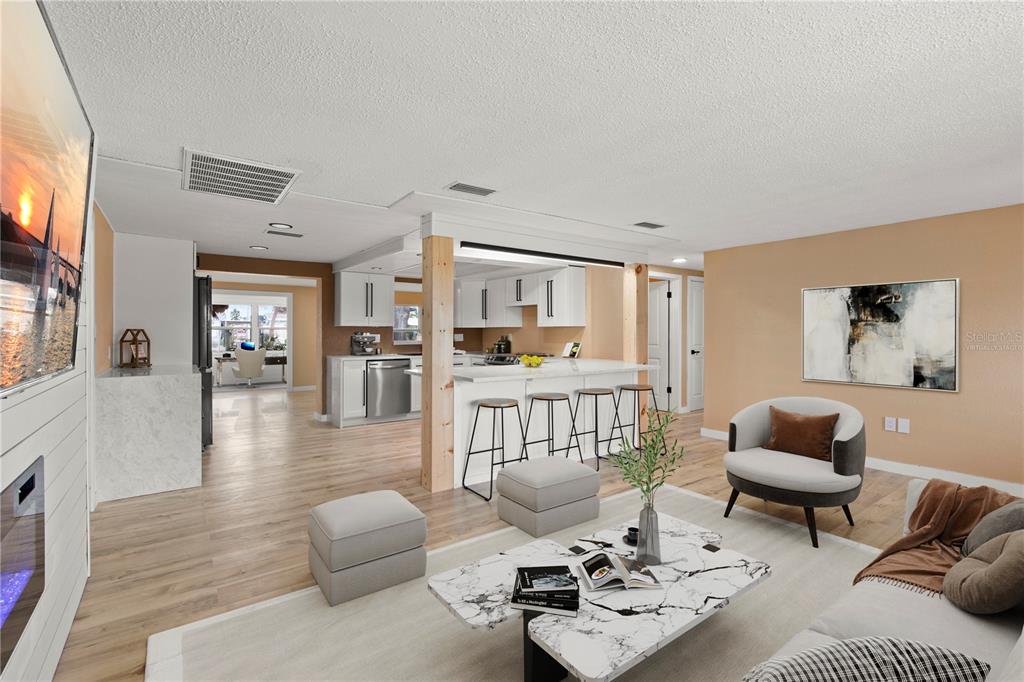 An open-concept living room and kitchen featuring white cabinetry, a marble-topped island, and wood flooring — 13626 ALLYN DRIVE, HUDSON, FL
