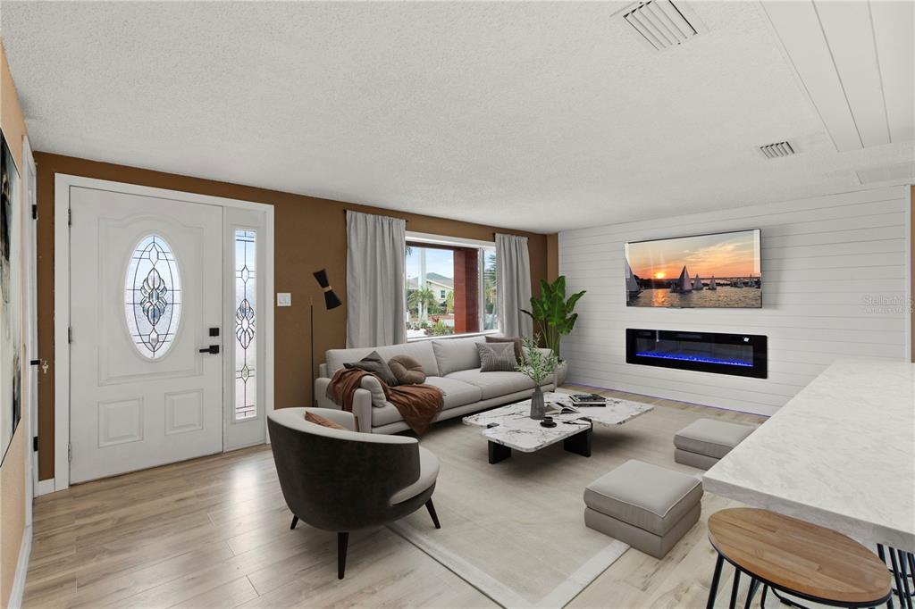 A living room features a white shiplap wall with a fireplace, television, and light flooring — 13626 ALLYN DRIVE, HUDSON, FL