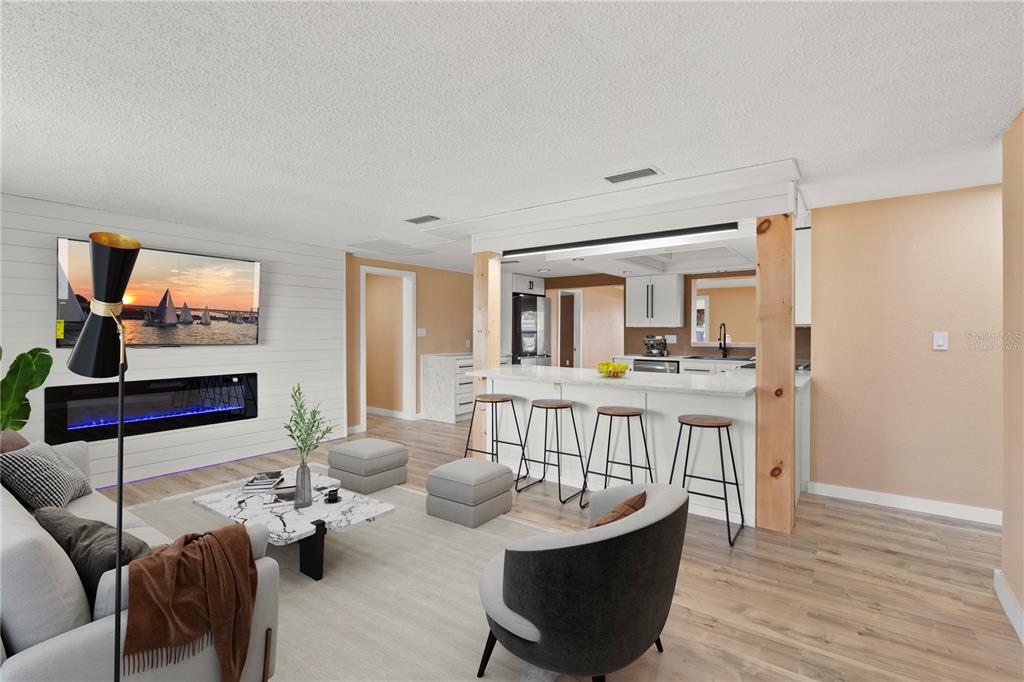 An open-concept living room and kitchen featuring a fireplace, white shiplap, and a breakfast bar — 13626 ALLYN DRIVE, HUDSON, FL