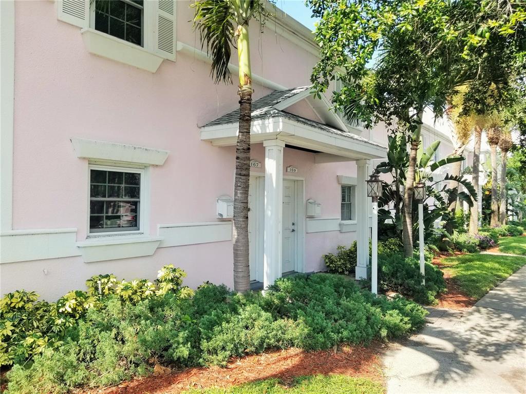 A pink two-story building features a covered entryway with two doors and landscaping — 169 POMPANO DRIVE SE, ST PETERSBURG, FL