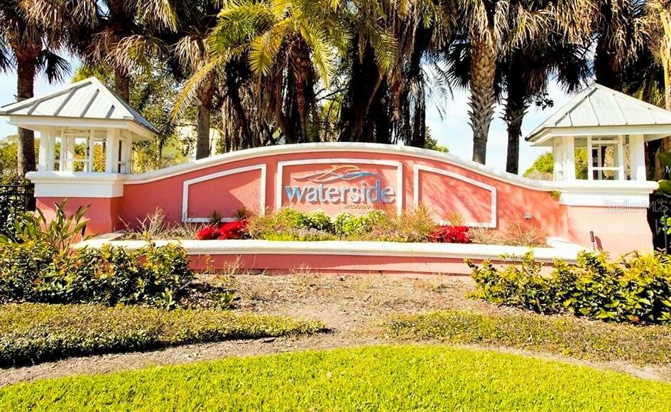 A salmon-colored community entrance sign with white trim is surrounded by palm trees — 169 POMPANO DRIVE SE, ST PETERSBURG, FL