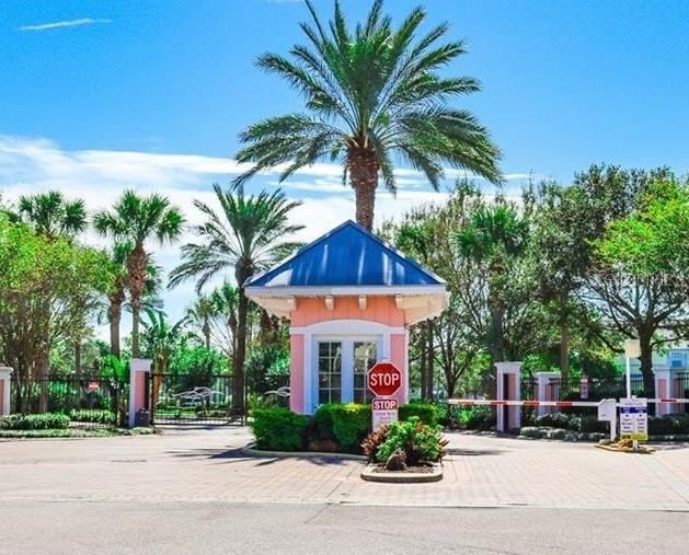 A gated community entrance features a pink guardhouse with a blue roof and palm trees — 169 POMPANO DRIVE SE, ST PETERSBURG, FL