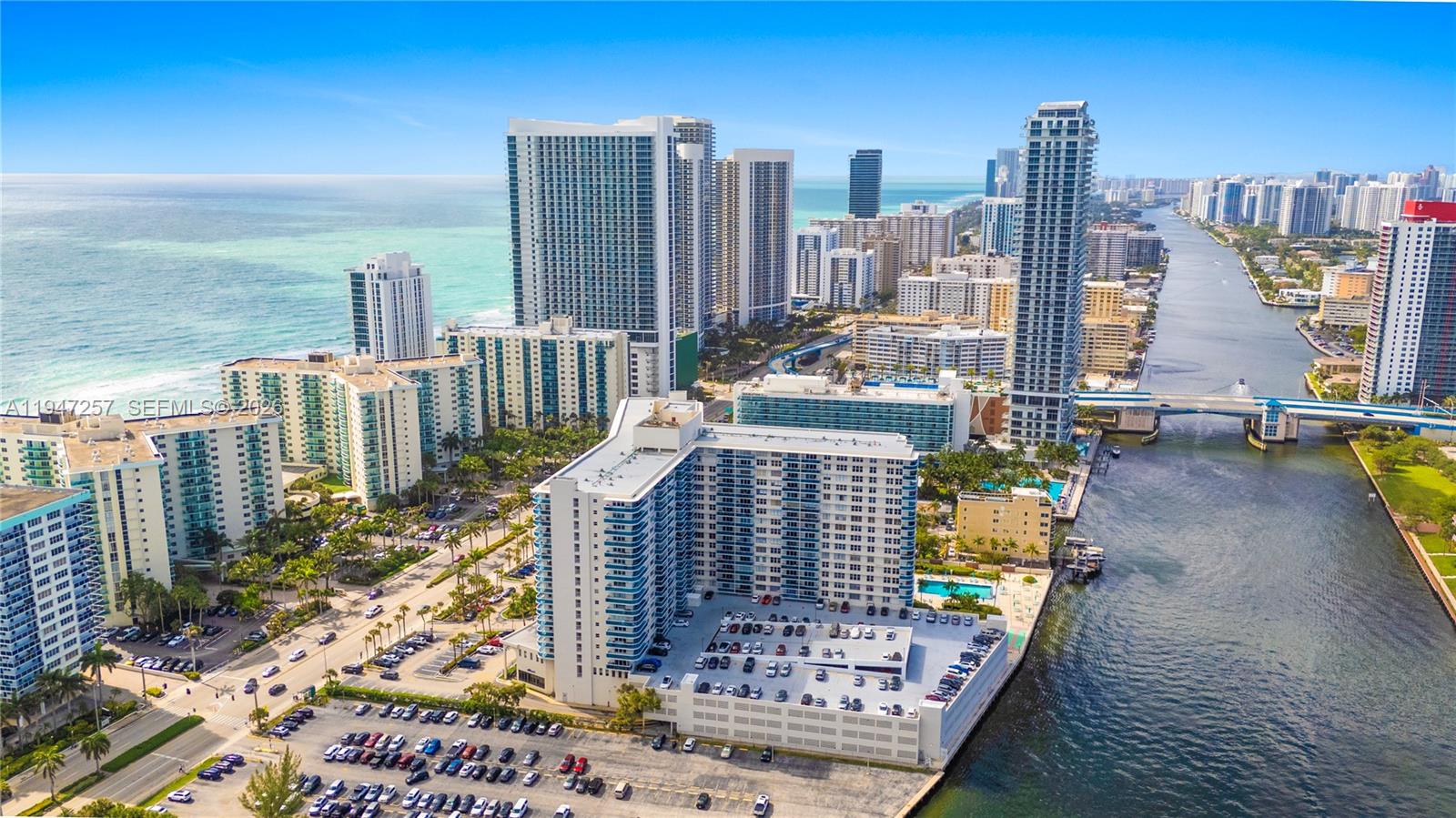 An aerial view shows high-rise apartment buildings along a canal and the ocean coastline — 3800 S Ocean Dr # 419, Hollywood FL 33019, HOLLYWOOD, FL