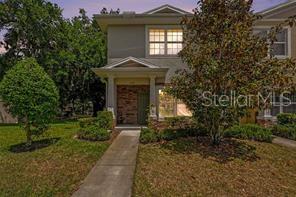 A two-story townhouse with a stone-accented entrance and a concrete walkway leading to the front door — 1112 HILLHURST DRIVE, WESLEY CHAPEL, FL