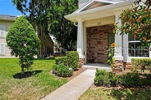 A stone-accented entryway leads to a front door under a covered porch with white columns — 1112 HILLHURST DRIVE, WESLEY CHAPEL, FL