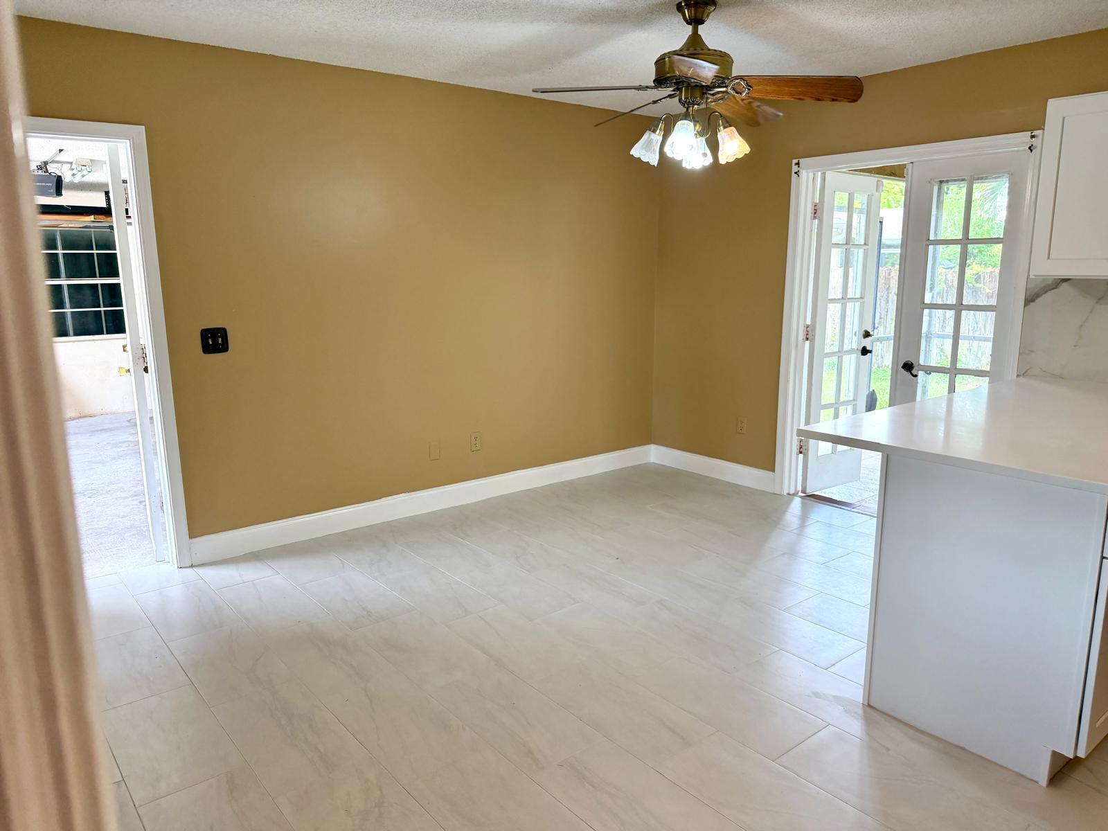 A dining area with tan walls, light tile flooring, a ceiling fan, and French doors — 1235 Rowayton Circle, Wellington FL 33414, WELLINGTON, FL