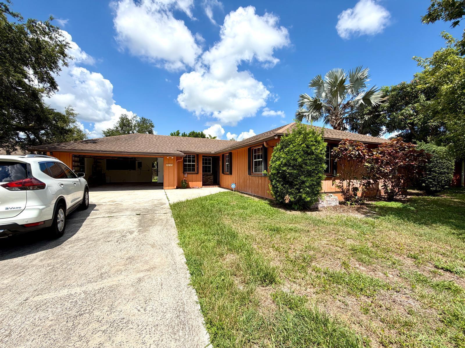 A single-story house with orange siding, a brown roof, and a driveway with a car — 1235 Rowayton Circle, Wellington FL 33414, WELLINGTON, FL