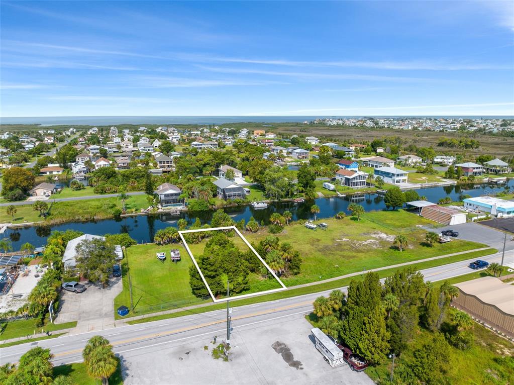 An aerial view shows a vacant, rectangular lot bordered by a road and a canal — 3329 SHOAL LINE BOULEVARD, HERNANDO BEACH, FL
