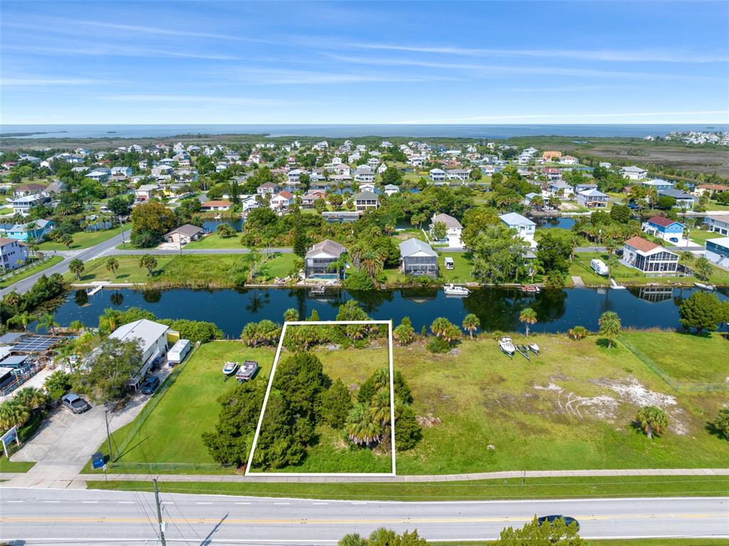 An aerial view shows a vacant, rectangular lot bordered by a road and a canal — 3329 SHOAL LINE BOULEVARD, HERNANDO BEACH, FL