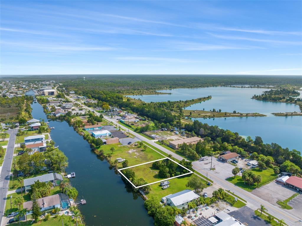 An aerial view shows a vacant, rectangular waterfront lot outlined in white beside a road — 3329 SHOAL LINE BOULEVARD, HERNANDO BEACH, FL