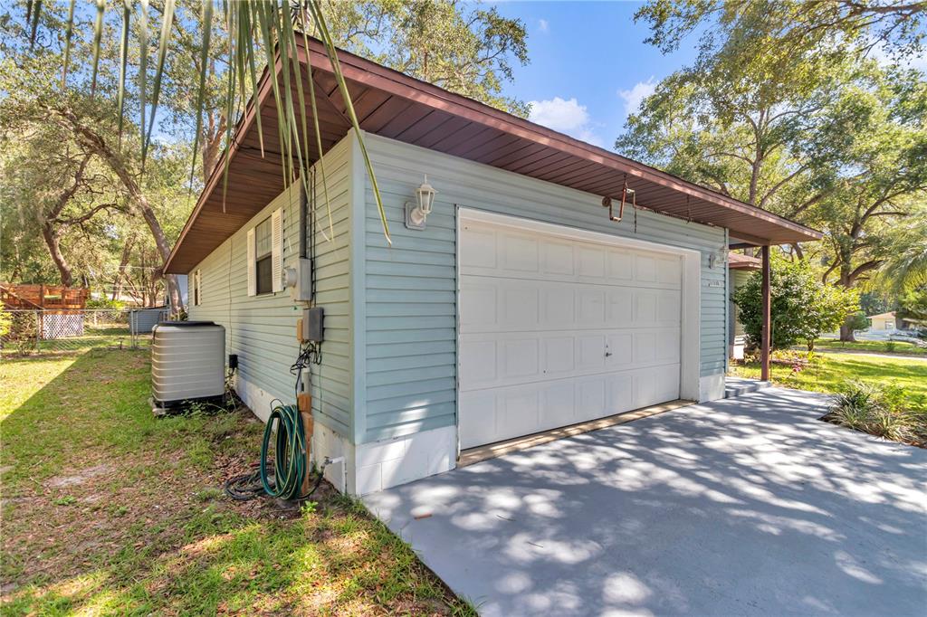 The exterior of a light blue garage with a white door and a concrete driveway — 16365 SE 17TH STREET, OCKLAWAHA, FL