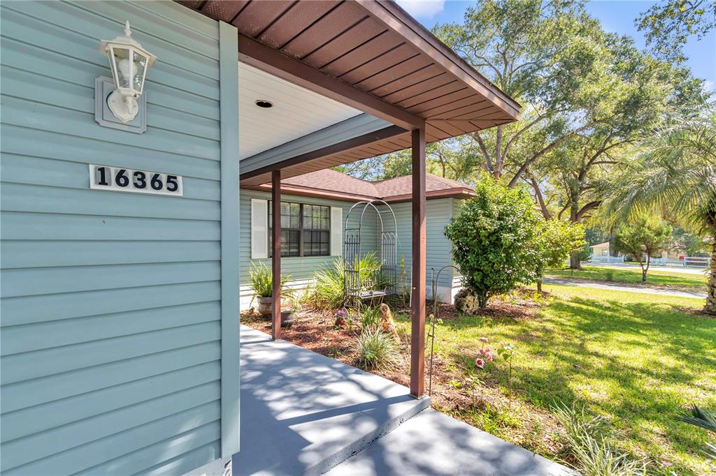 A light blue house features a covered front porch with a dark brown support post — 16365 SE 17TH STREET, OCKLAWAHA, FL