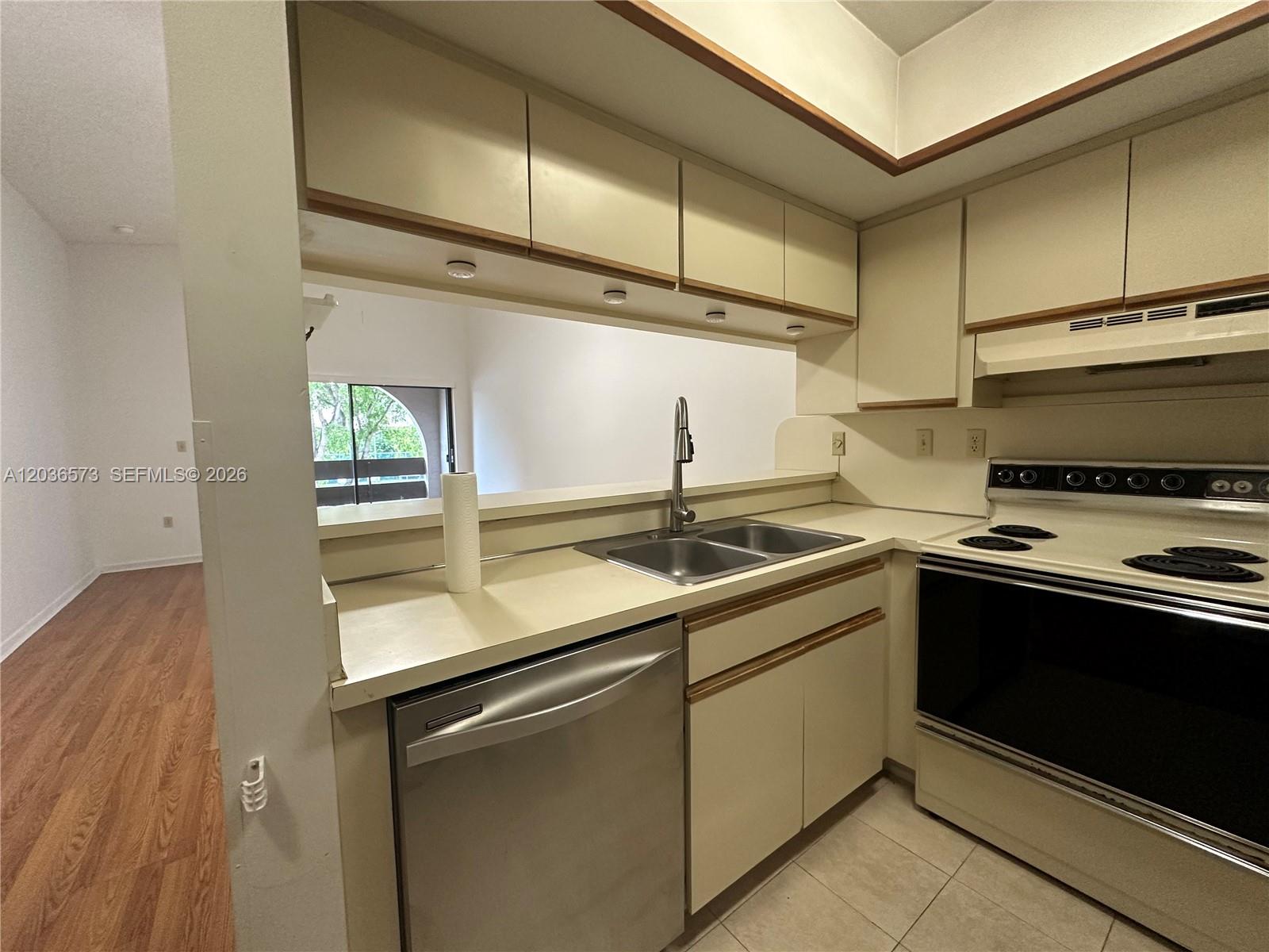 A kitchen features light-colored cabinetry, a stainless steel dishwasher, and a pass-through window — 8999 SW 123rd Ct # 212, Miami FL 33186, MIAMI, FL