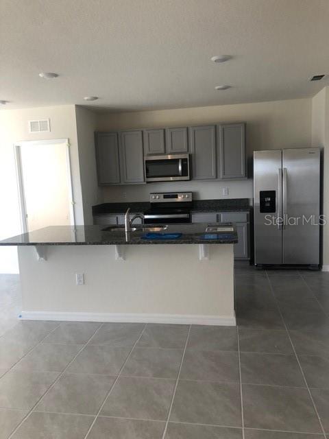 A kitchen features gray cabinets, stainless steel appliances, and a granite-topped island with seating — 2952 LONG POND DRIVE, LAKELAND, FL
