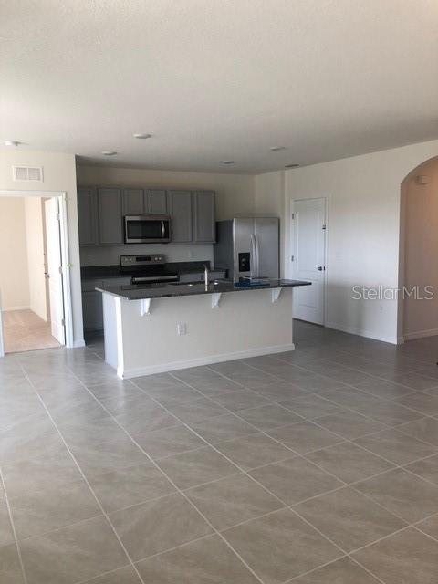 A kitchen features gray cabinets, stainless steel appliances, and a central island with granite countertops — 2952 LONG POND DRIVE, LAKELAND, FL