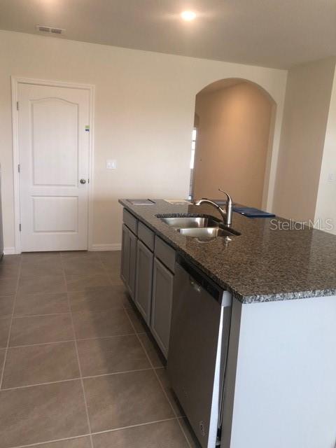 A kitchen island with a granite countertop and stainless steel sink sits on tiled flooring — 2952 LONG POND DRIVE, LAKELAND, FL