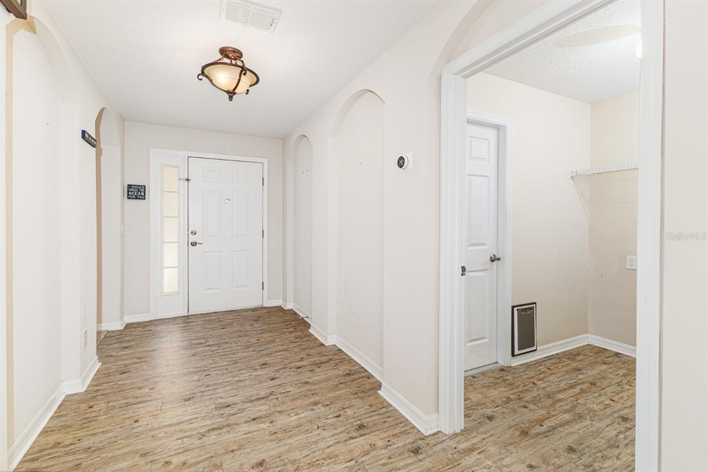 An entryway with wood-look flooring, arched wall niches, and a white front door — 7233 WAKEVIEW DRIVE, DAVENPORT, FL