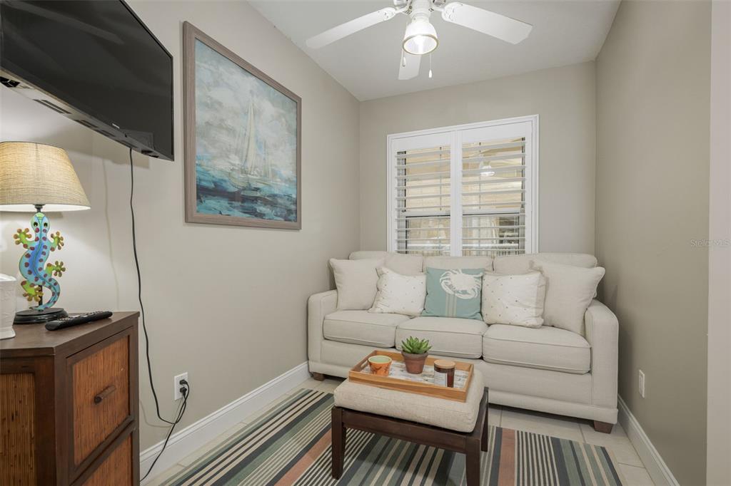 A small living room features a beige sofa, a striped rug, and a wall-mounted television — 4650 LINKS VILLAGE DRIVE UNIT C206, PONCE INLET, FL