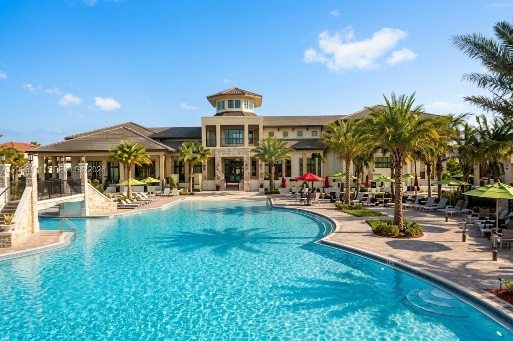 A large swimming pool sits in front of a multi-story building with palm trees — 10620 NW 88th St # 221, Doral FL 33178, DORAL, FL