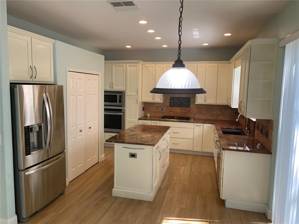 A kitchen features white cabinets, granite countertops, a central island, and stainless steel appliances — 4527 RIVERTON DRIVE, ORLANDO, FL