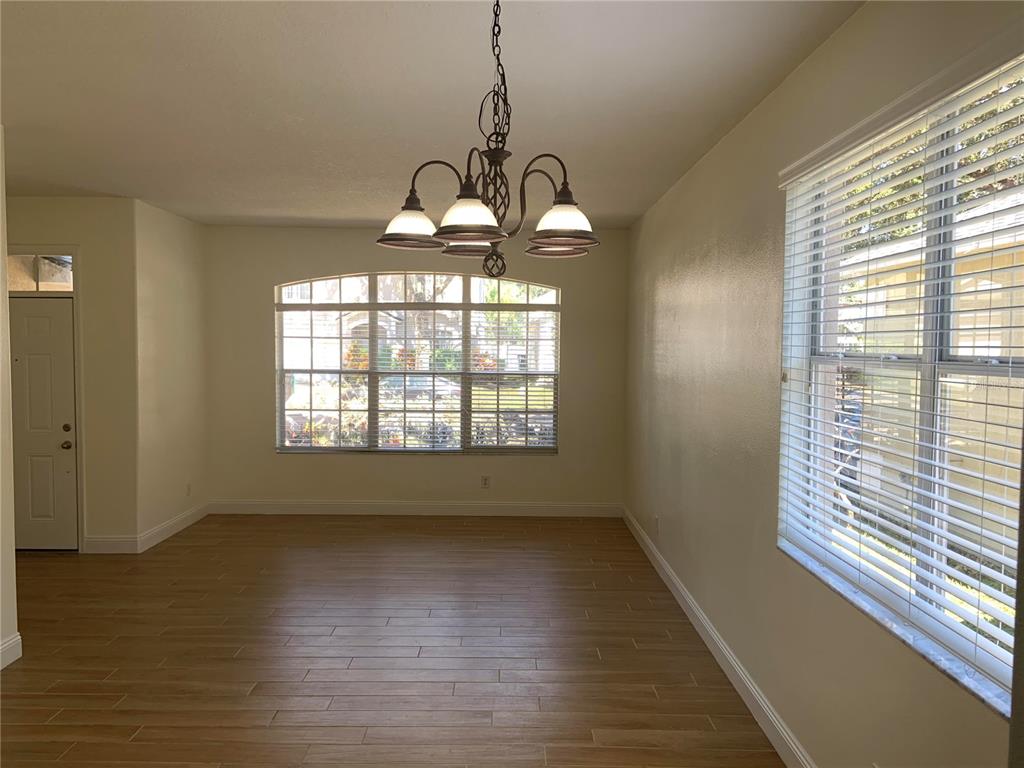 An empty dining room features light wood-look tile flooring, a chandelier, and two large windows — 4527 RIVERTON DRIVE, ORLANDO, FL