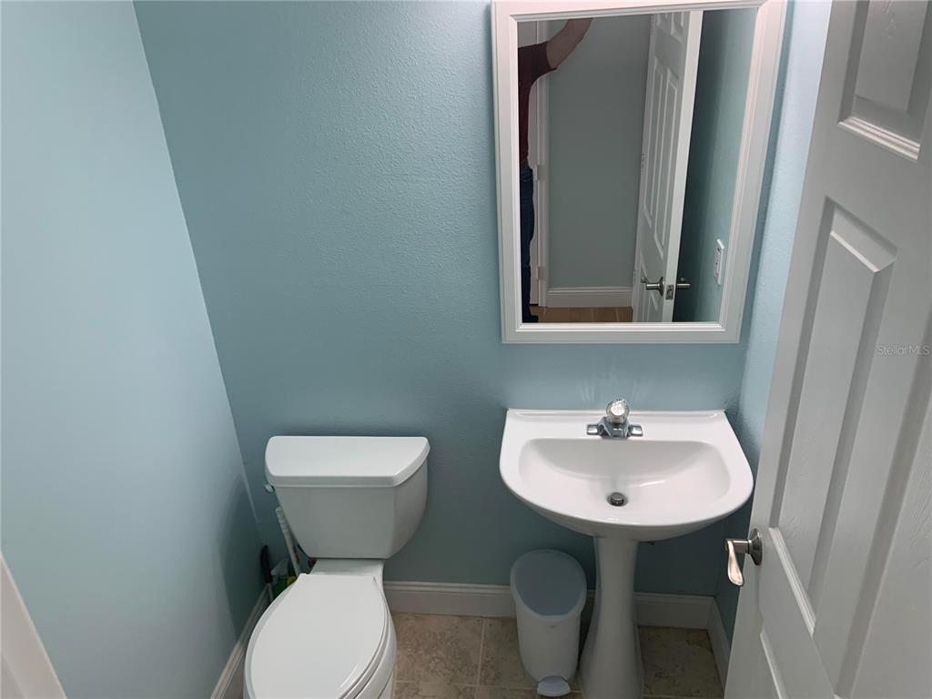 A small bathroom features light blue walls, a white pedestal sink, and a toilet — 4527 RIVERTON DRIVE, ORLANDO, FL