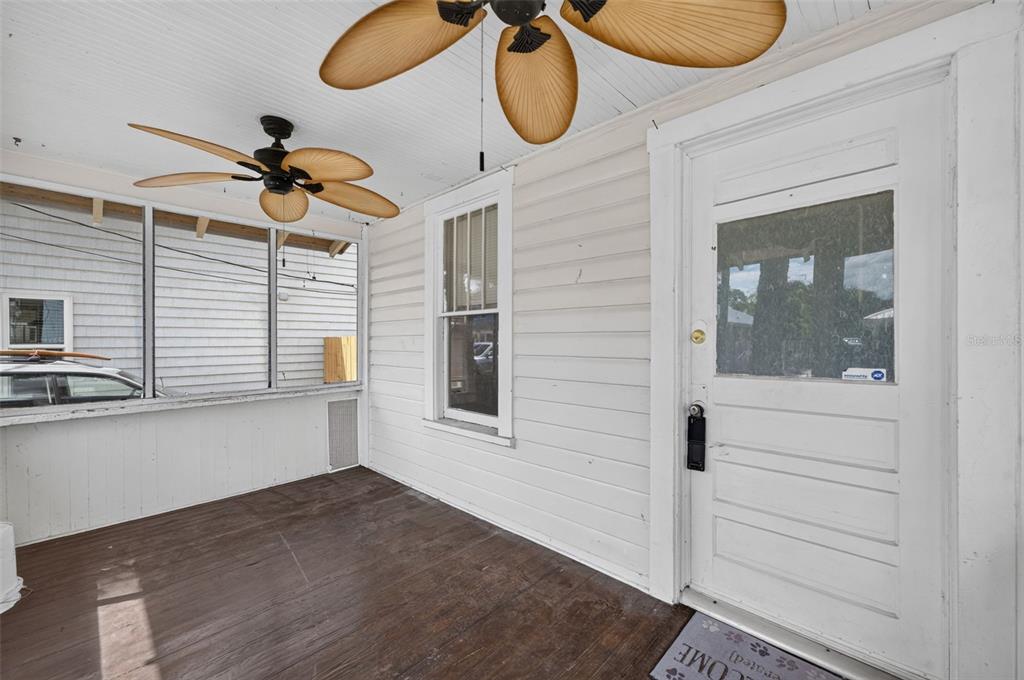 A covered porch features white horizontal siding, a wooden floor, and two ceiling fans — 309 RUSH STREET, NEW SMYRNA BEACH, FL