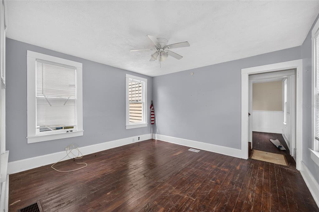 An empty room with gray walls, dark wood floors, a ceiling fan, and white trim — 309 RUSH STREET, NEW SMYRNA BEACH, FL