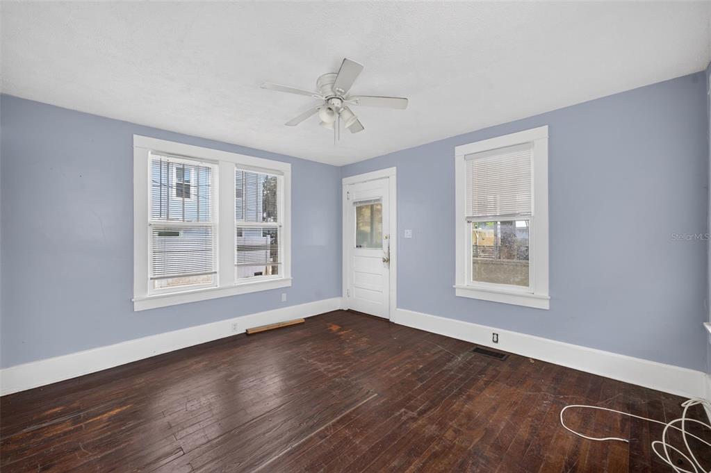 An empty room with light blue walls, dark wood floors, a ceiling fan, and windows — 309 RUSH STREET, NEW SMYRNA BEACH, FL