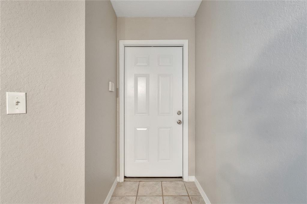 A white six-panel door stands at the end of a small tiled entryway — 8825 LATREC AVENUE UNIT 6103, ORLANDO, FL