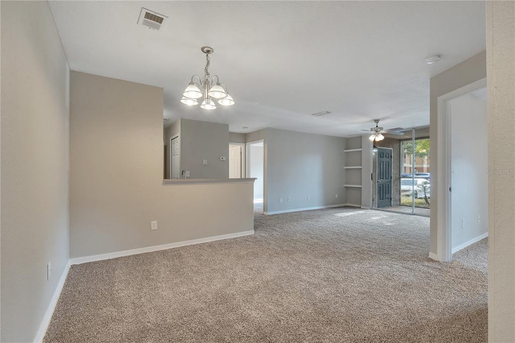 A carpeted living and dining area features a chandelier, ceiling fan, and sliding glass doors — 8825 LATREC AVENUE UNIT 6103, ORLANDO, FL