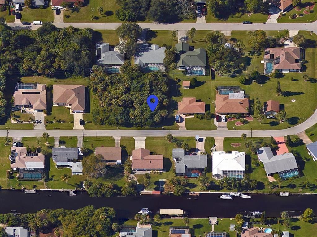 This is an aerial view of a vacant, wooded residential lot marked by a blue pin — 18425 DRIGGERS AVENUE, PORT CHARLOTTE, FL