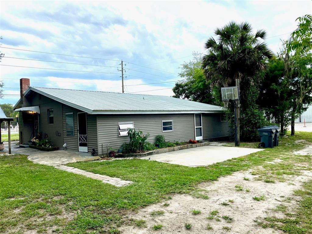 A single-story house with gray siding, a metal roof, and a concrete patio — 3801 US HIGHWAY 17 92 N, DAVENPORT, FL