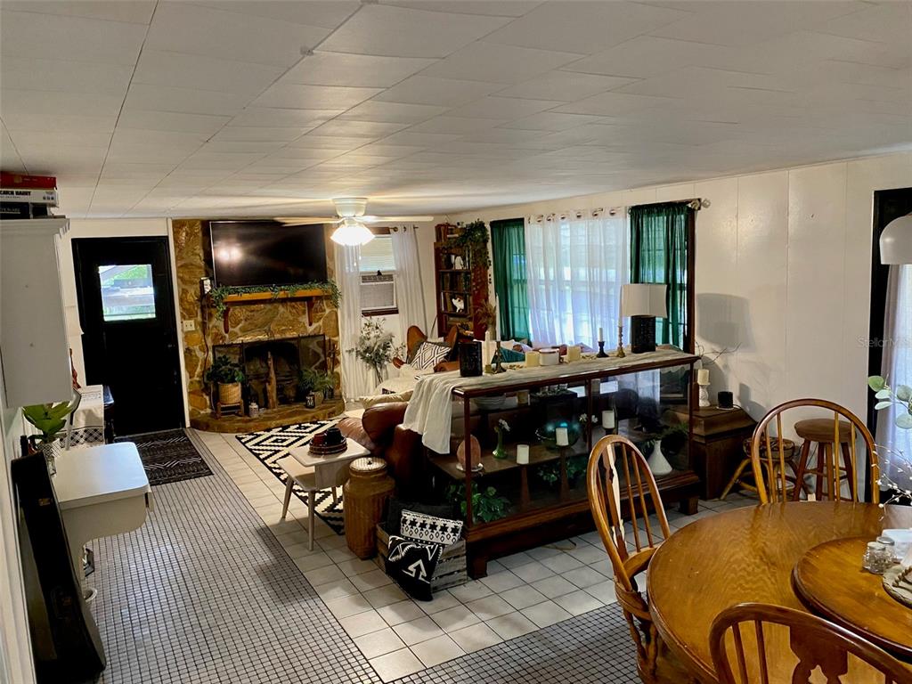 A living room with a stone fireplace, tile flooring, and a wooden dining table — 3801 US HIGHWAY 17 92 N, DAVENPORT, FL
