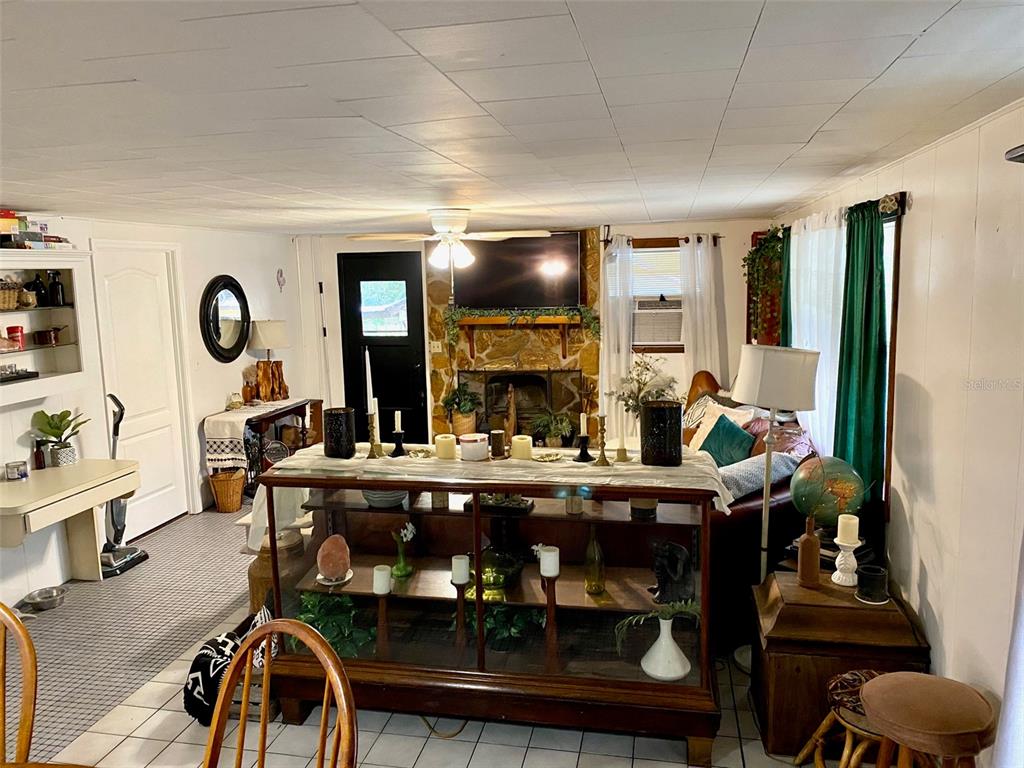 A living room features a stone fireplace, a ceiling fan, and a glass-front display cabinet — 3801 US HIGHWAY 17 92 N, DAVENPORT, FL