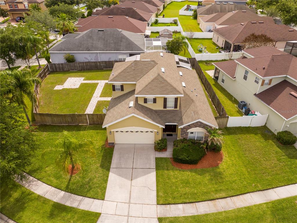 An aerial view shows a two-story suburban house with a fenced backyard and driveway — 1986 MARSH HAWK DRIVE, ORLANDO, FL