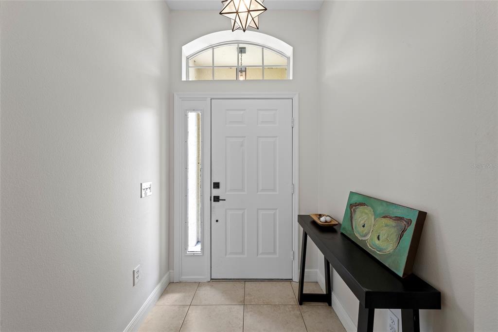 A bright entryway features a white front door, a transom window, and a console table — 6222 BLUEFLOWER COURT, BRADENTON, FL